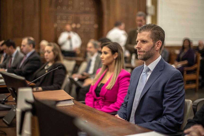 Eric Trump, dressed in suit and tie, sits in court. People can be seen in the gallery behind him.