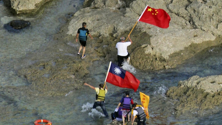 Pro-China activists carrying Chinese and Taiwanese national flags walk on the disputed island