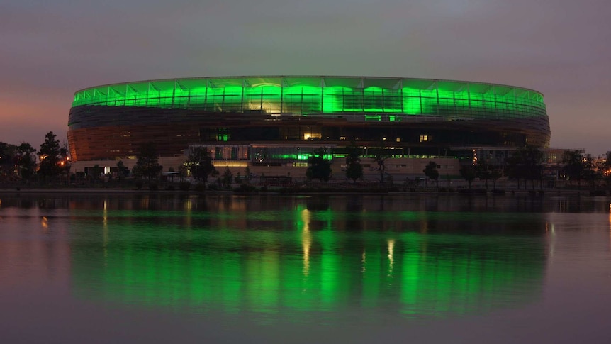 New Perth stadium illuminated in green in the early morning, view looking across the river.