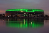 New Perth stadium illuminated in green in the early morning, view looking across the river.