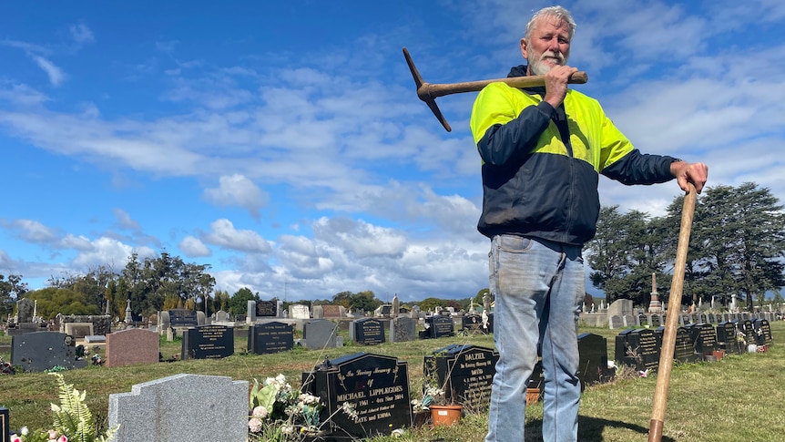 man standing with a shovel and pick. 