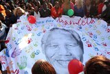 Well-wishers outside hospital in Pretoria hold a giant banner showing Nelson Mandela.
