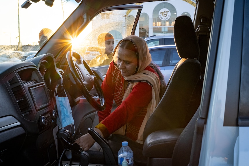 a woman inside a car leaning over looking for a face mask