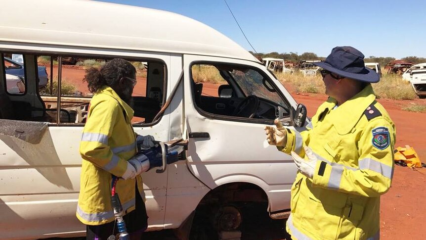 Ngaanyatjarra emergency response volunteer practices using the jaws of life on a broken down vehicle.