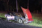 A burnt-out Ferrari on the side of a road.