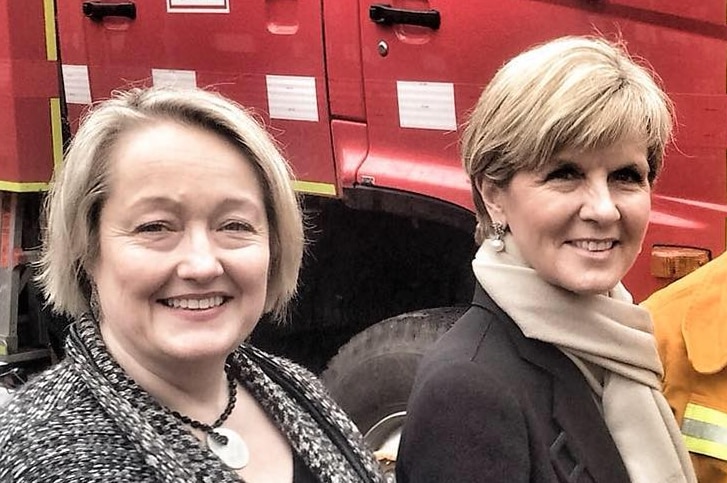 Louise Staley stands alongside Julie Bishop and a CFA firefighter in front of a red CFA truck.