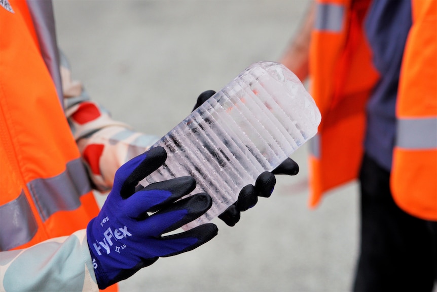 Close up of hands holding a cylinder-shaped piece of ice