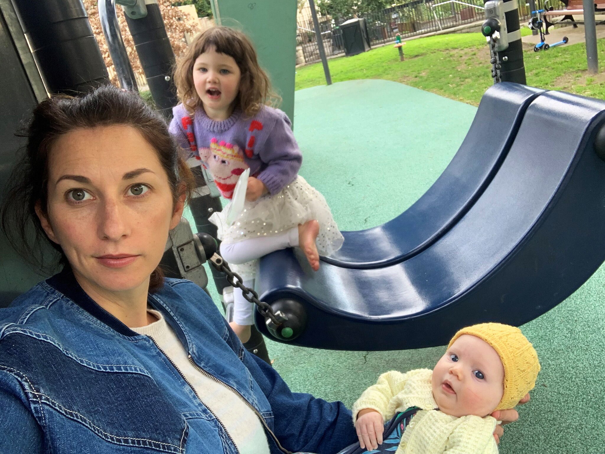 Veronica and her two young children are sitting in a playground