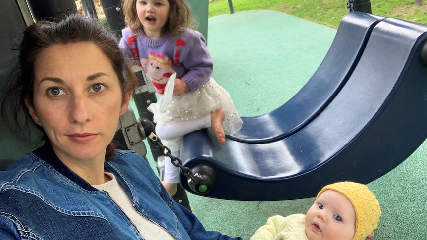 Veronica and her two young children are sitting in a playground