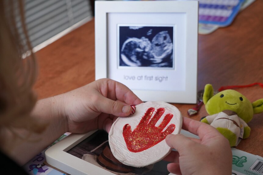 A woman holding a child's handprint.