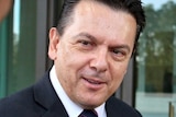 Nick Xenophon smiles as he speaks to a reporter, whose head is also in shot, out of focus in the foreground.