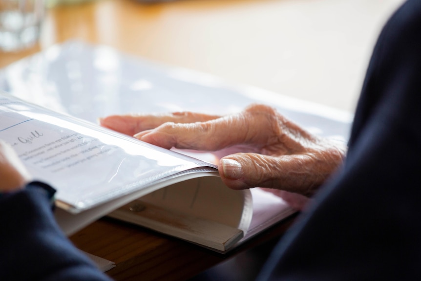 An older person's hands hold a magazine