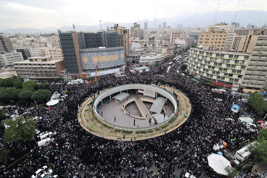 A view of a city from above with streets crowded with people wearing black