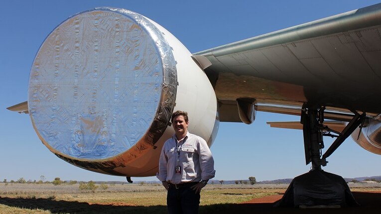 A man stands next to a taped up aircraft engine.