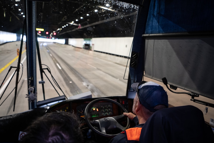 A large underground tunnel, seen from behind a man driving a construction vehicle