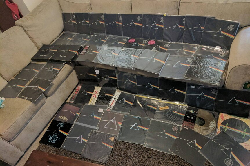 About 50 copies of the Pink Floyd record Dark Side Of The Moon lay on a couch and floor.