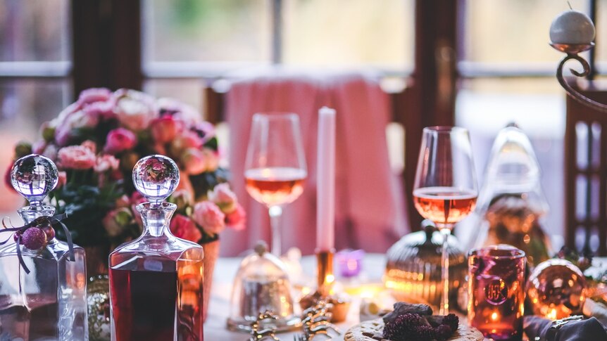 A table set for a dinner party with flowers, candles and wine.