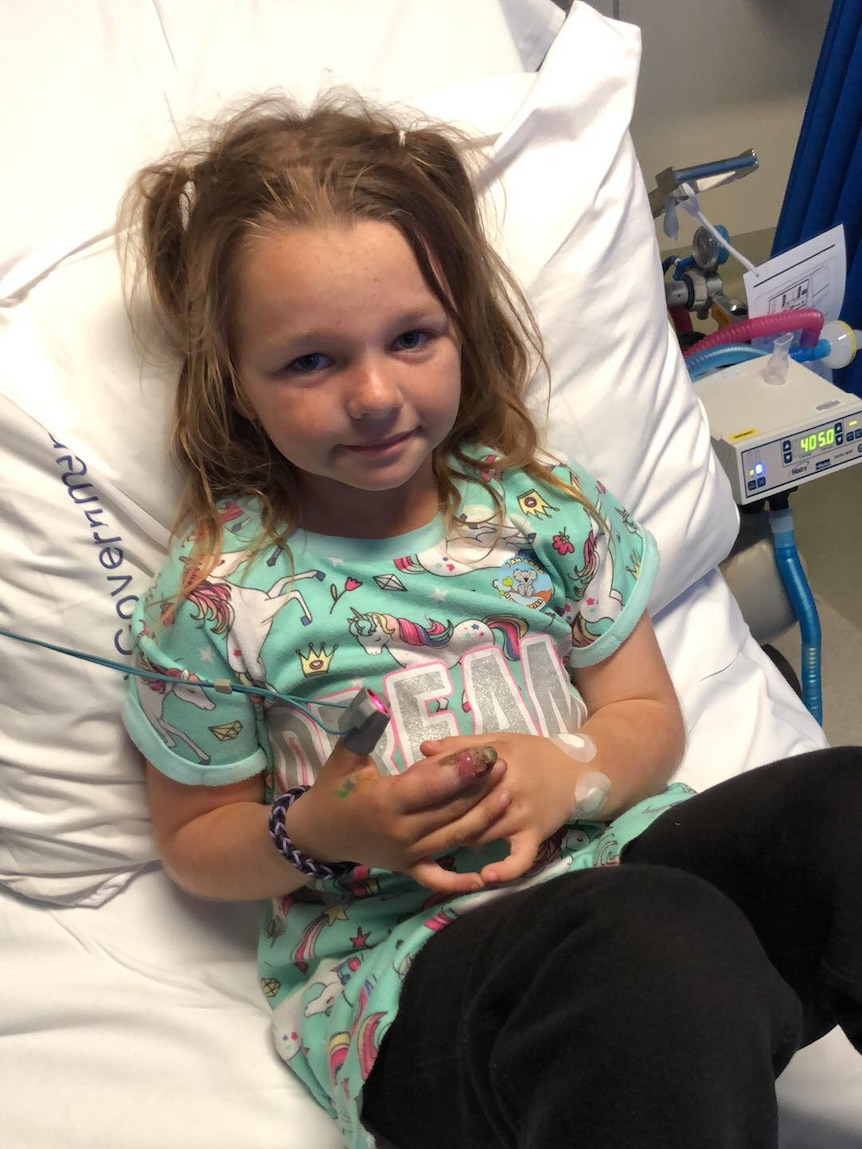 A young girl lying in a hospital bed.