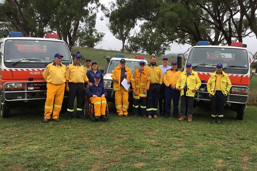 RFS crew in yellow fire suits stand with two emergency vehicles