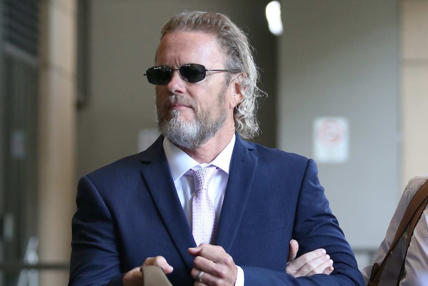 Craig McLachlan outside the Melbourne Magistrates' Court with his partner holding his arm.