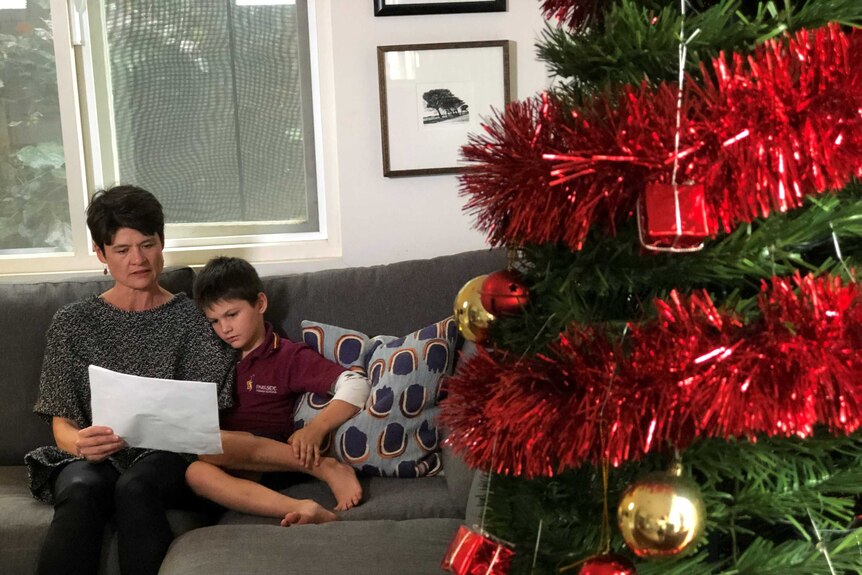 Sarah Langley sits with her son Alex on a couch looking at photos.