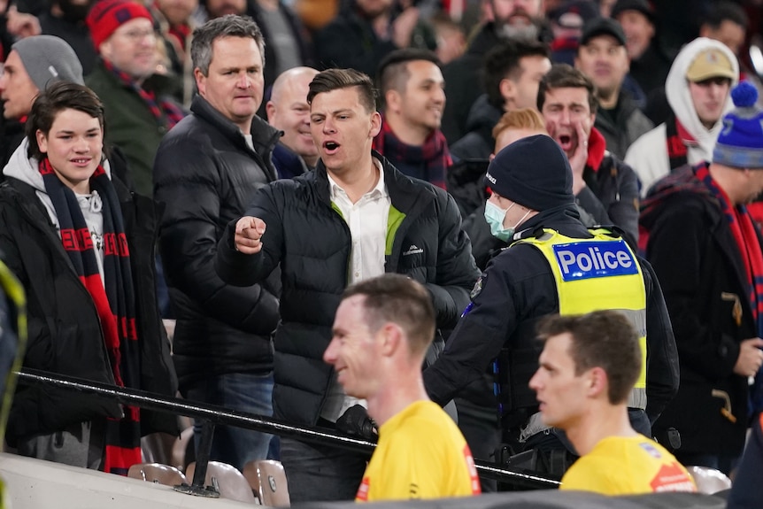 Spectators gesture from the grandstand as AFL umpires leave the field at the MCG.