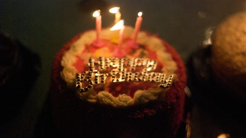 Birthday cake with candles alight. Happy Birthday sign - generic