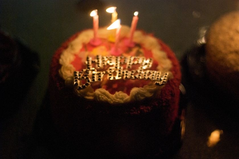 Birthday cake with candles alight. Happy Birthday sign - generic