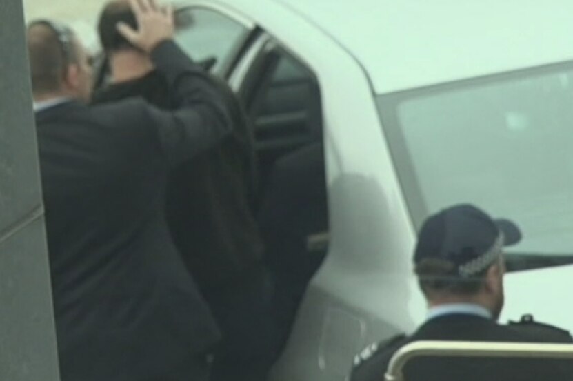 Marcus Stanford is escorted into a waiting car at Sydney Airport by NSW Police
