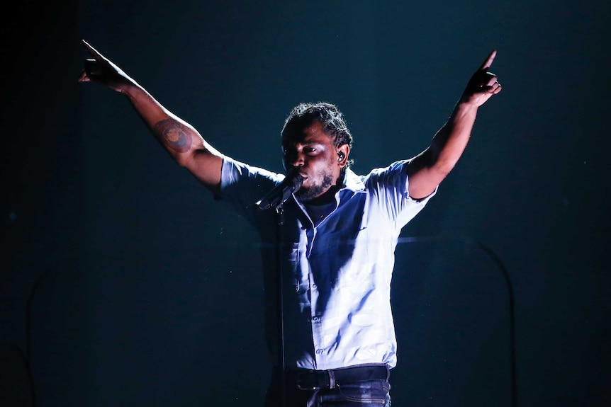 Kendrick Lamar points to the sky at the Grammys.