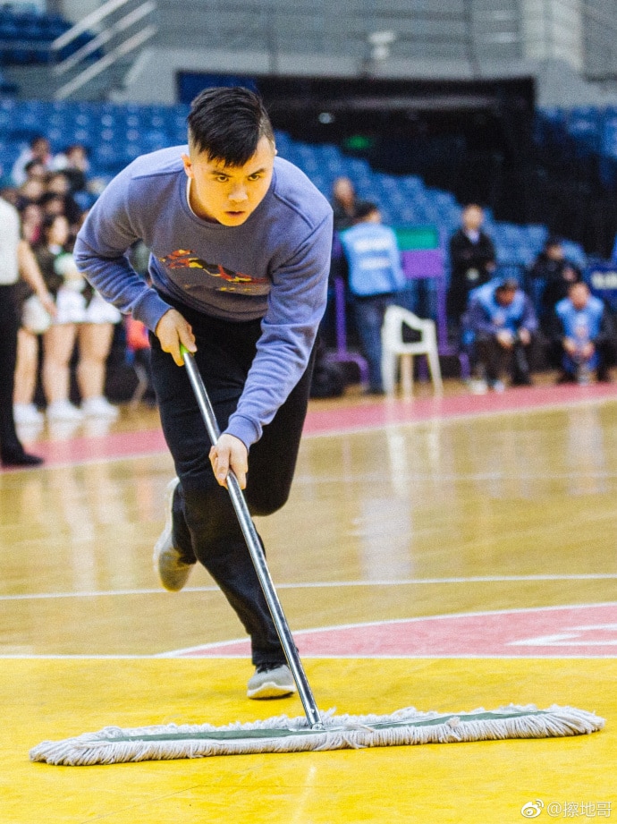 Meng Fei runs onto court using a mop, he looks very focused.