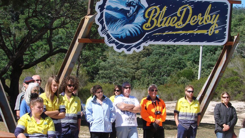 Members of the first Derby Green Army team standing below a large 'Blue Derby' Mountain Bike Trail sign.