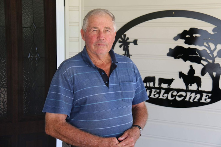 John Cowley stands in front of his house.