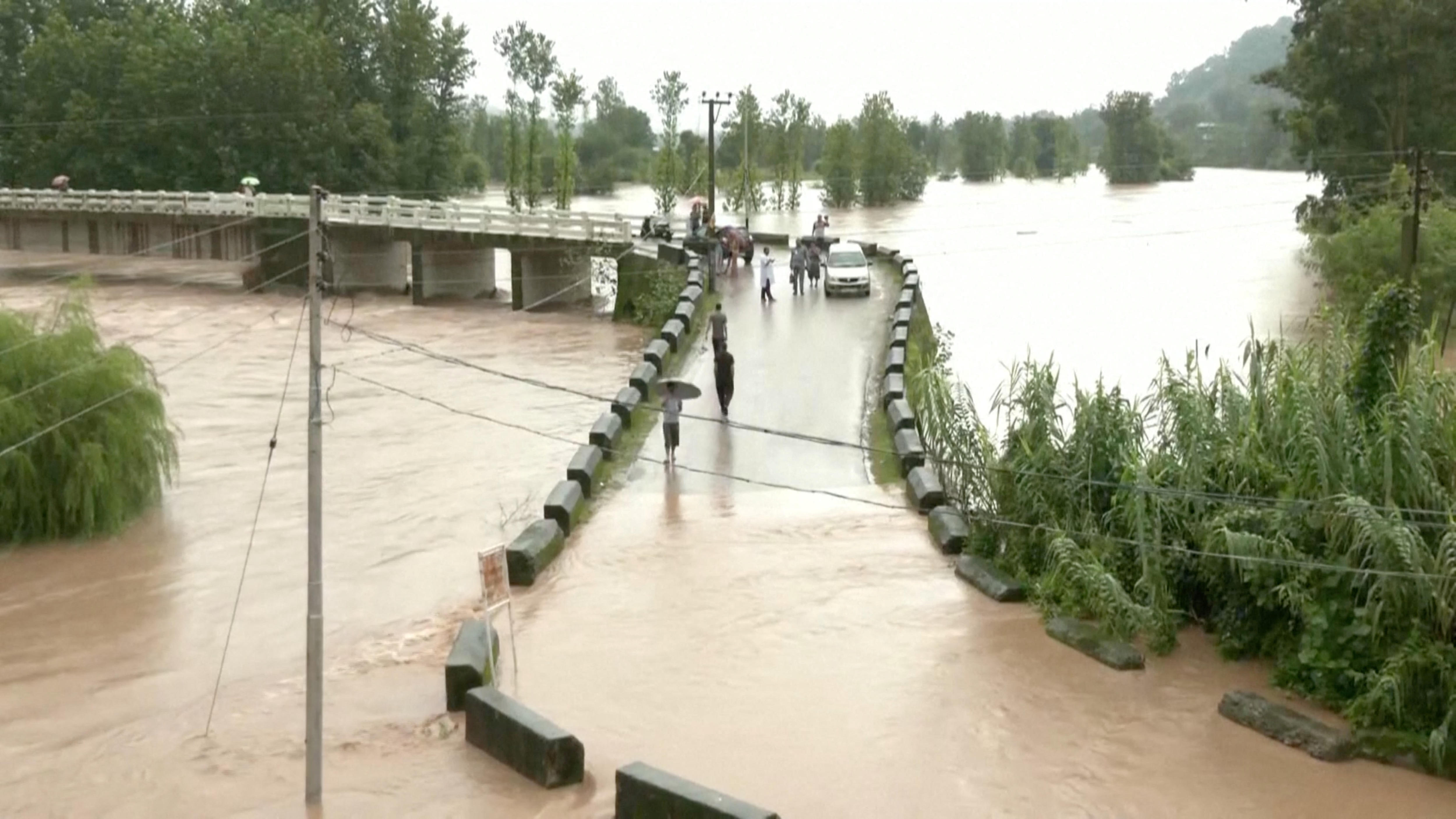 People walking across a flooded bridge.