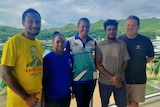Four para athletes from Papua New Guinea stand next to a white man from Australia, with mountains in the backdrop. 