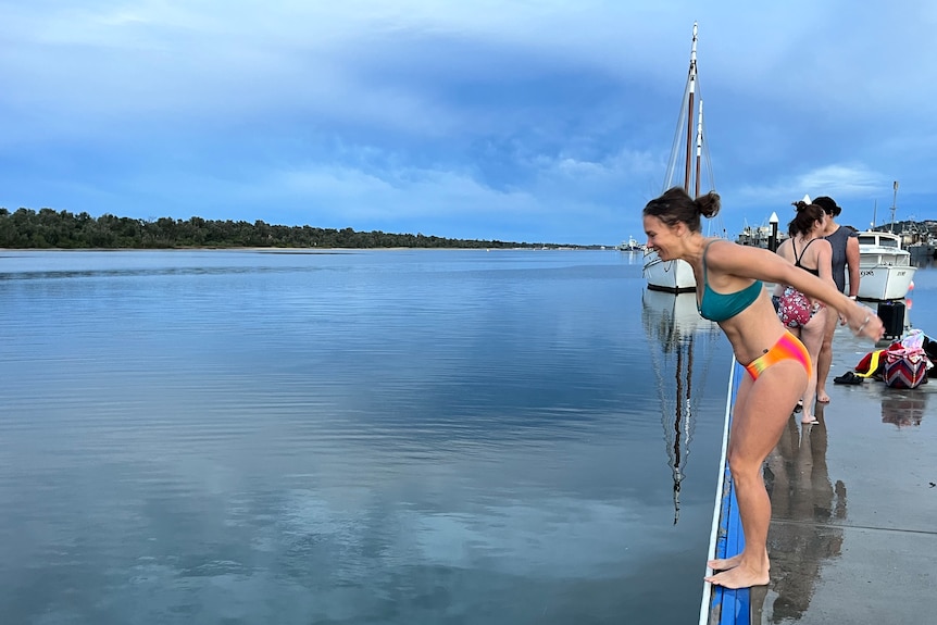 A woman standing on a jetty ready to jump into cold seawater