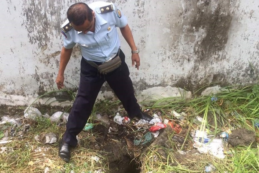 A police officer stands over the tunnel exit hole the men escaped through.