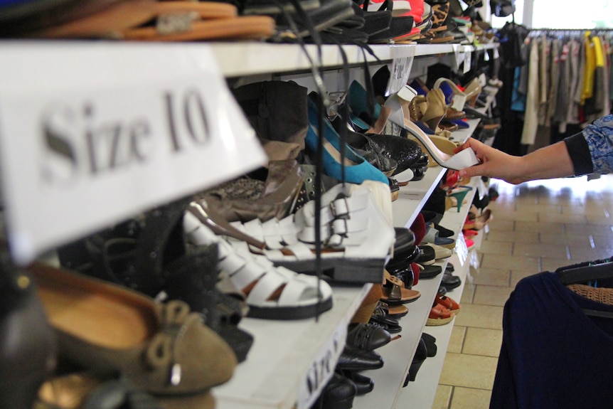 A woman looks at second-hand shoes at an op shop
