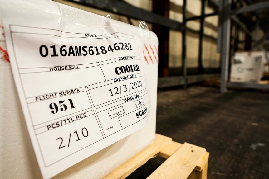 A document with a flight number and name is sticky taped onto a container.