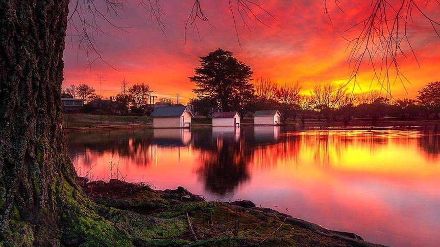 a pink and orange sunset reflected on a lake