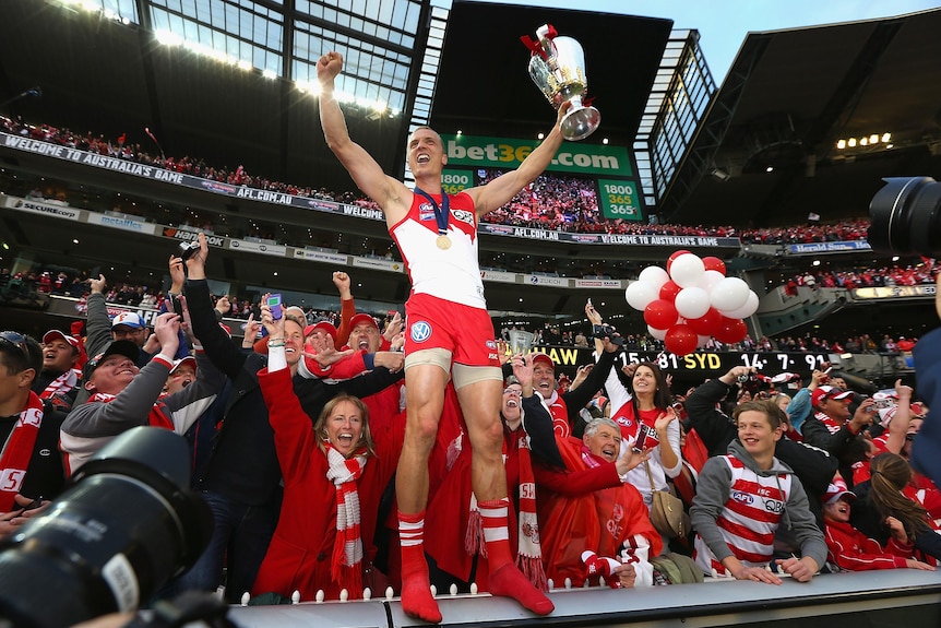 Ted Richards of the Sydney Swans celebrates with the premiership cup and the crowd.