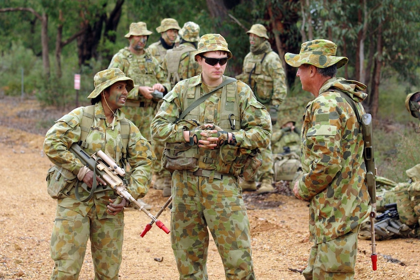 Private Punitha Perumal chats with other troops in bushland.