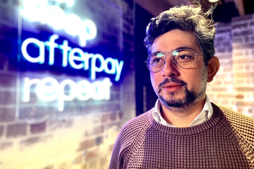 Damian in the Afterpay office with the logo neo sign behind him.