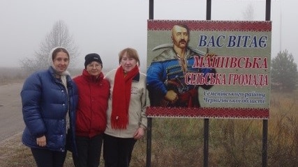 A group of people standing in front of a sign on a drab day in Eastern Europe.