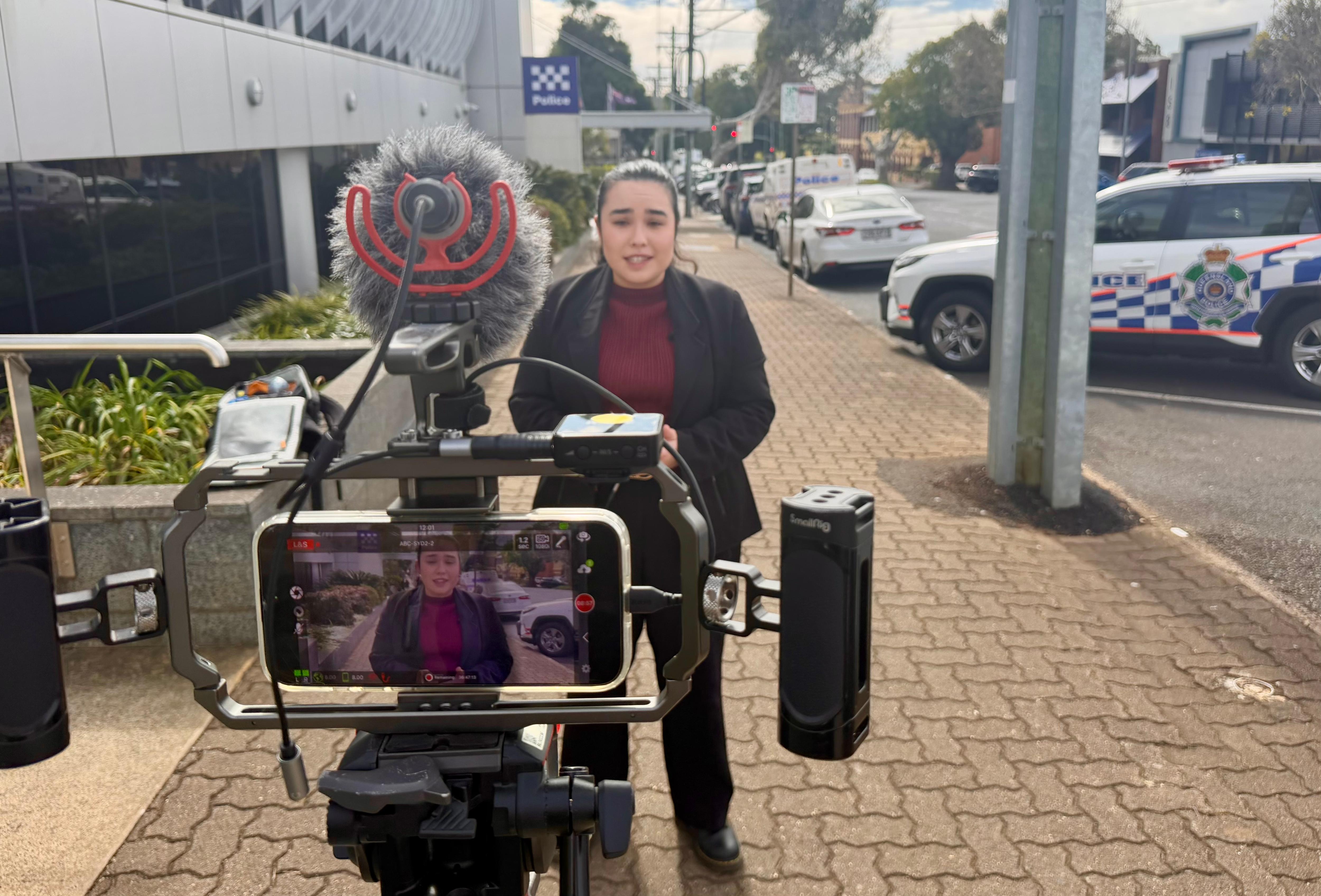 grace nakamura in black blazer outside with a camera