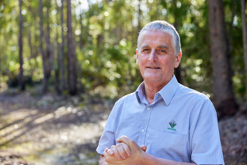 A man in a WAPRES shirt stands infront of a forest