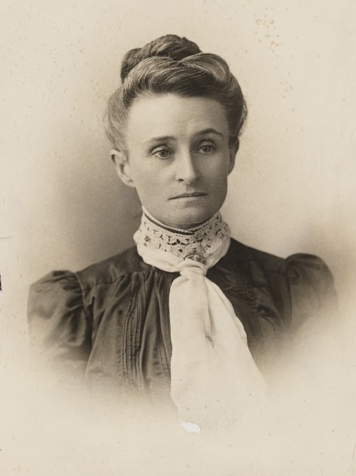 Old photo of Edith Cowan, she is not smiling or looking at camera. She wears a dark dress and a white neck piece.