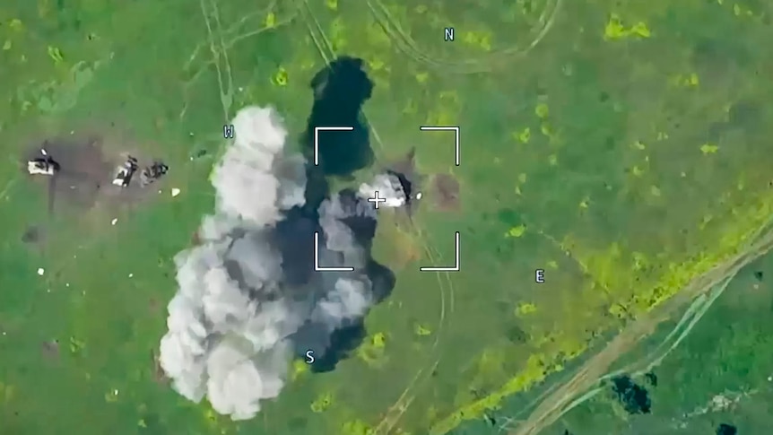 An aerial view of smoke from an explosive attack in a field.