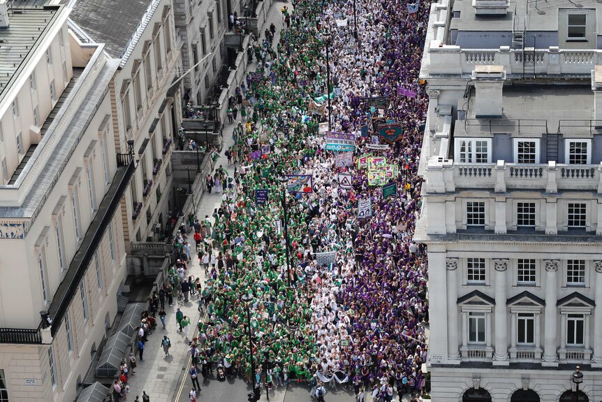 Thousands of people march in the formation of green, white and purple strips.