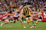 Hawthorn player Jordan Lewis kicking under pressure from Sydney players